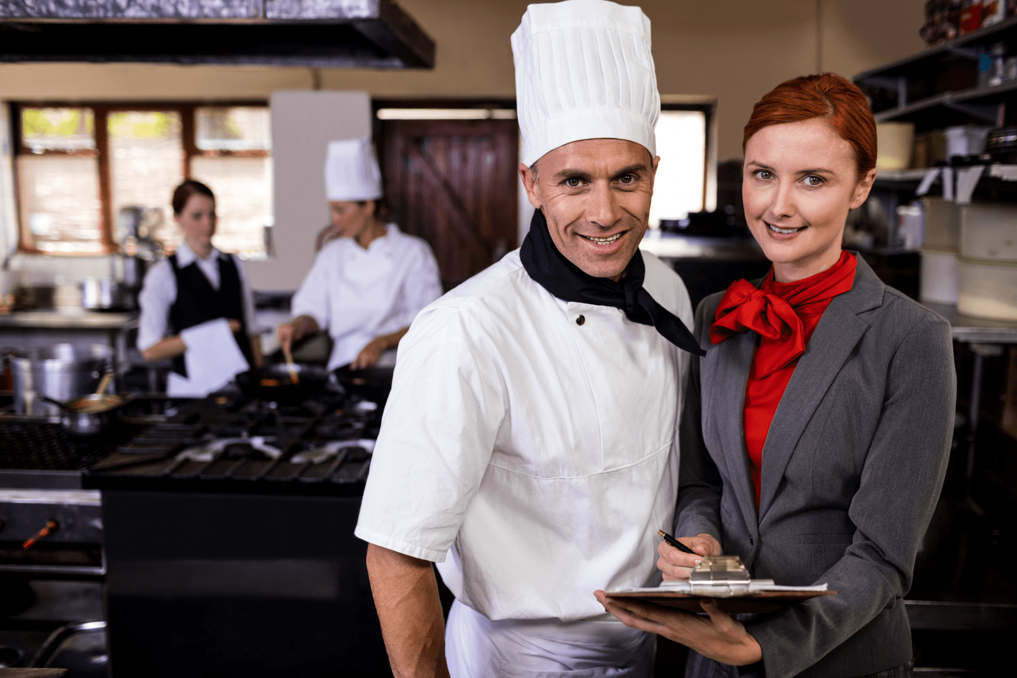 Executive chef in chef hat with restaurant supervisor in commercial kitchen